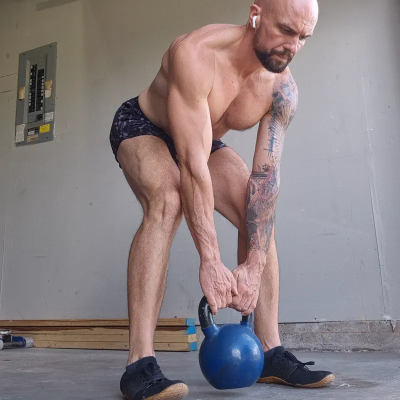 Straight leg kettlebell deadlift with both hands on the bell between the legs