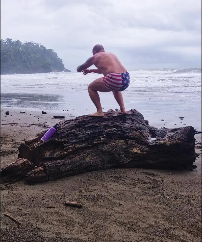 Josh landing in a low squat on top of a driftwood log at Playa Ventanas