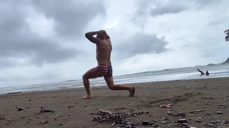 Josh doing a walking lunge on dark sand at Playa Ventanas with his hands on his head